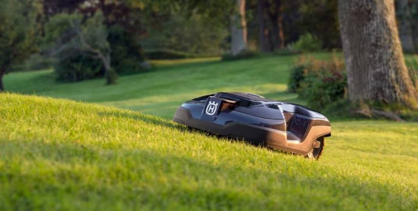 Image of a Husqvarna Automower mowing a hilly lawn.