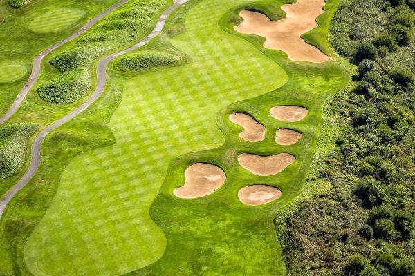 Photo of a robotic lawn mower for golf course greenskeepers automatically cutting the grass of the golf course they manage.