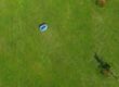 A commercial robot mower cutting grass in a large field.