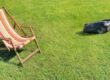 A Segway robot mower operating near a lawn chair.