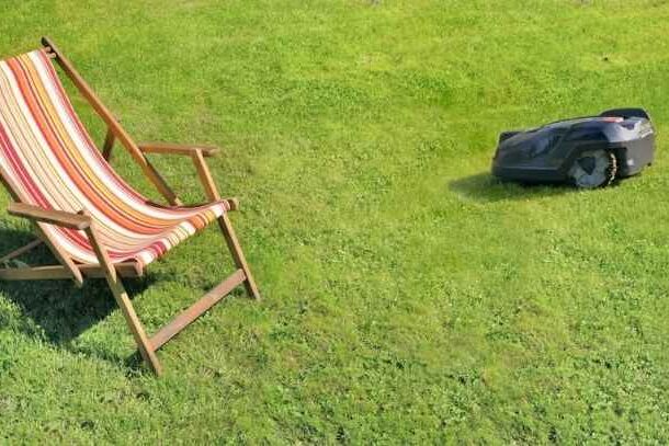 A Segway robot mower operating near a lawn chair.